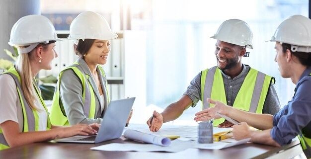 Engineers and technicians in hard hats meeting around a table