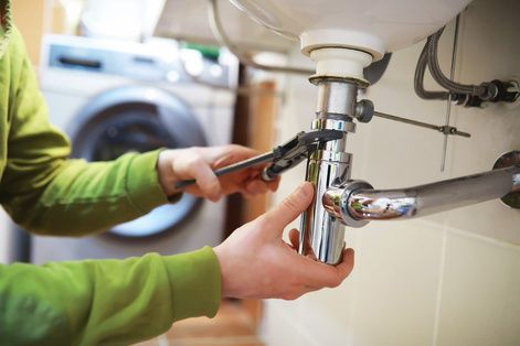 Plumber fitting pipework under a sink